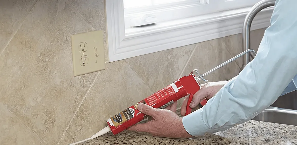 Handyman applying caulk along a kitchen backsplash and countertop seam in Duluth, MN